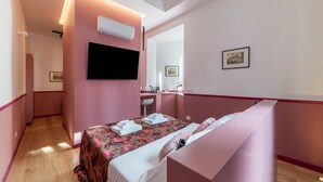 Una habitación de hotel con una cama, un televisor de pantalla plana, un espejo y un pequeño escritorio con una silla.