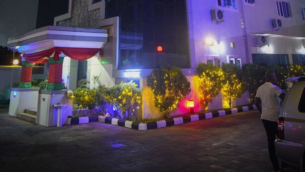 A hotel with a modern design, featuring a prominent sign at the top and a well-lit entrance area. - UG Wils Hotels and Suites  (Calabar)