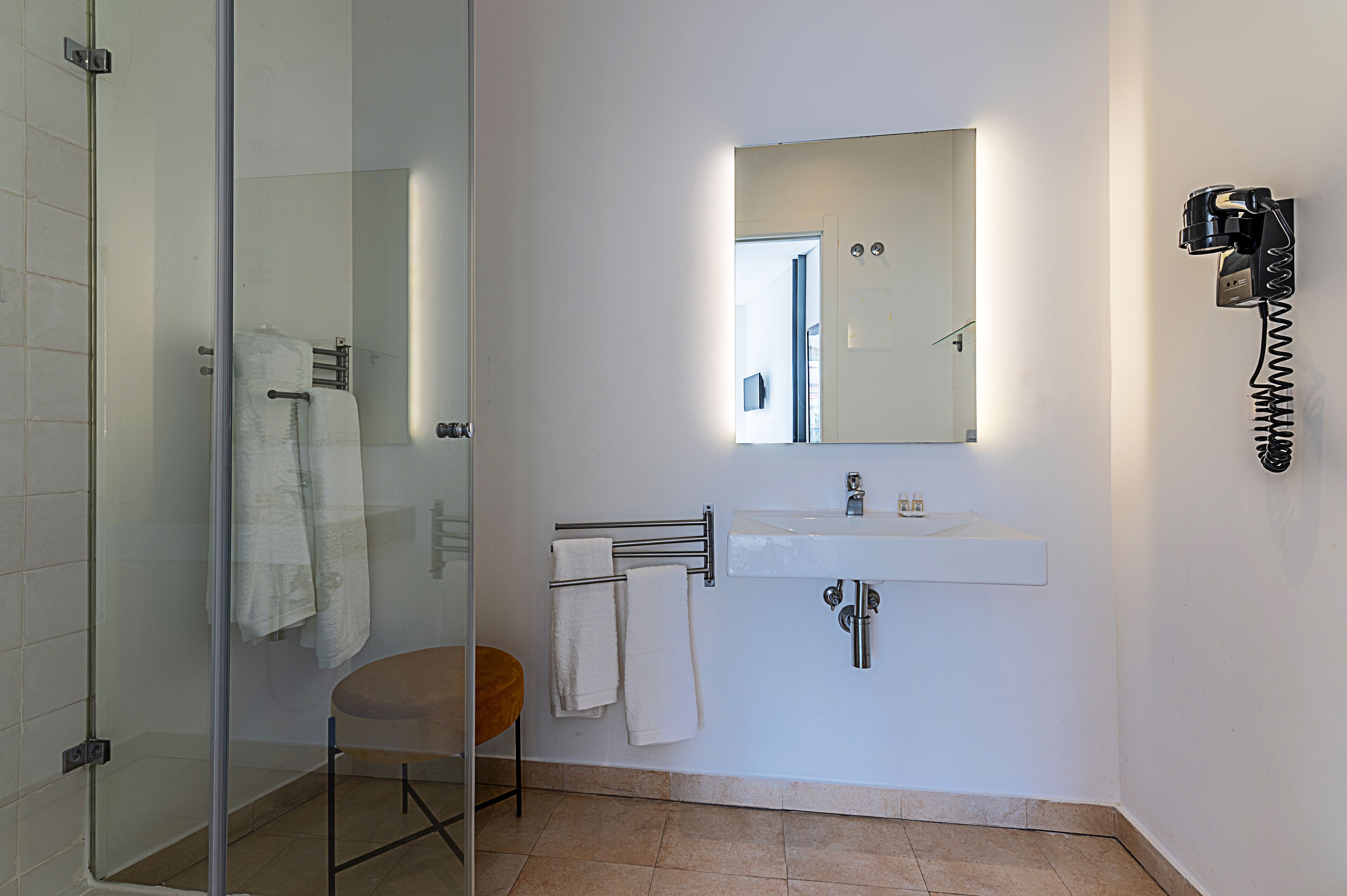 A modern bathroom with a glass shower enclosure, a white sink, and a towel rack.