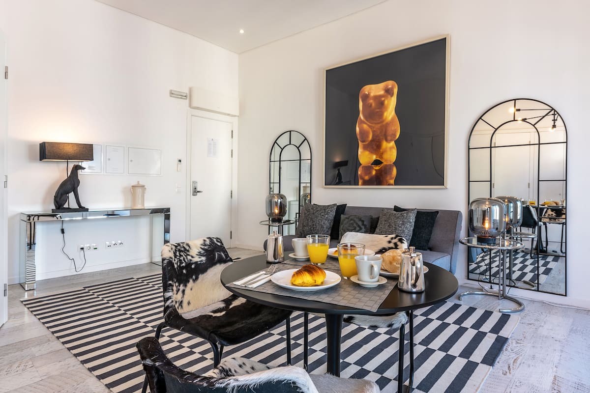 A modern dining area with a round table, black and white checkered rug, and a black and white sofa.