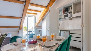A breakfast setting with a table set for two, a microwave, and a cabinet with kitchen items. - Portas do Céu Apartments (Lisbon)