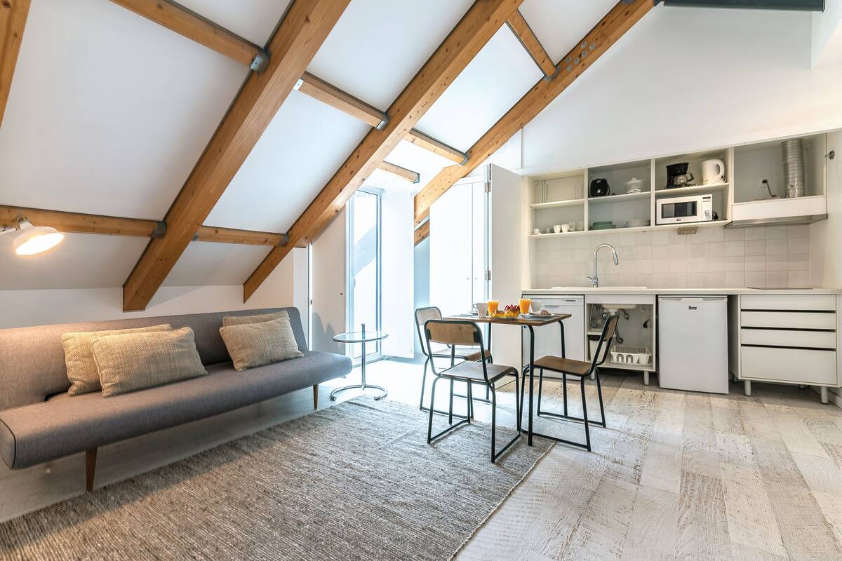 A modern loft-style apartment with a dining area, kitchenette, and a sofa.