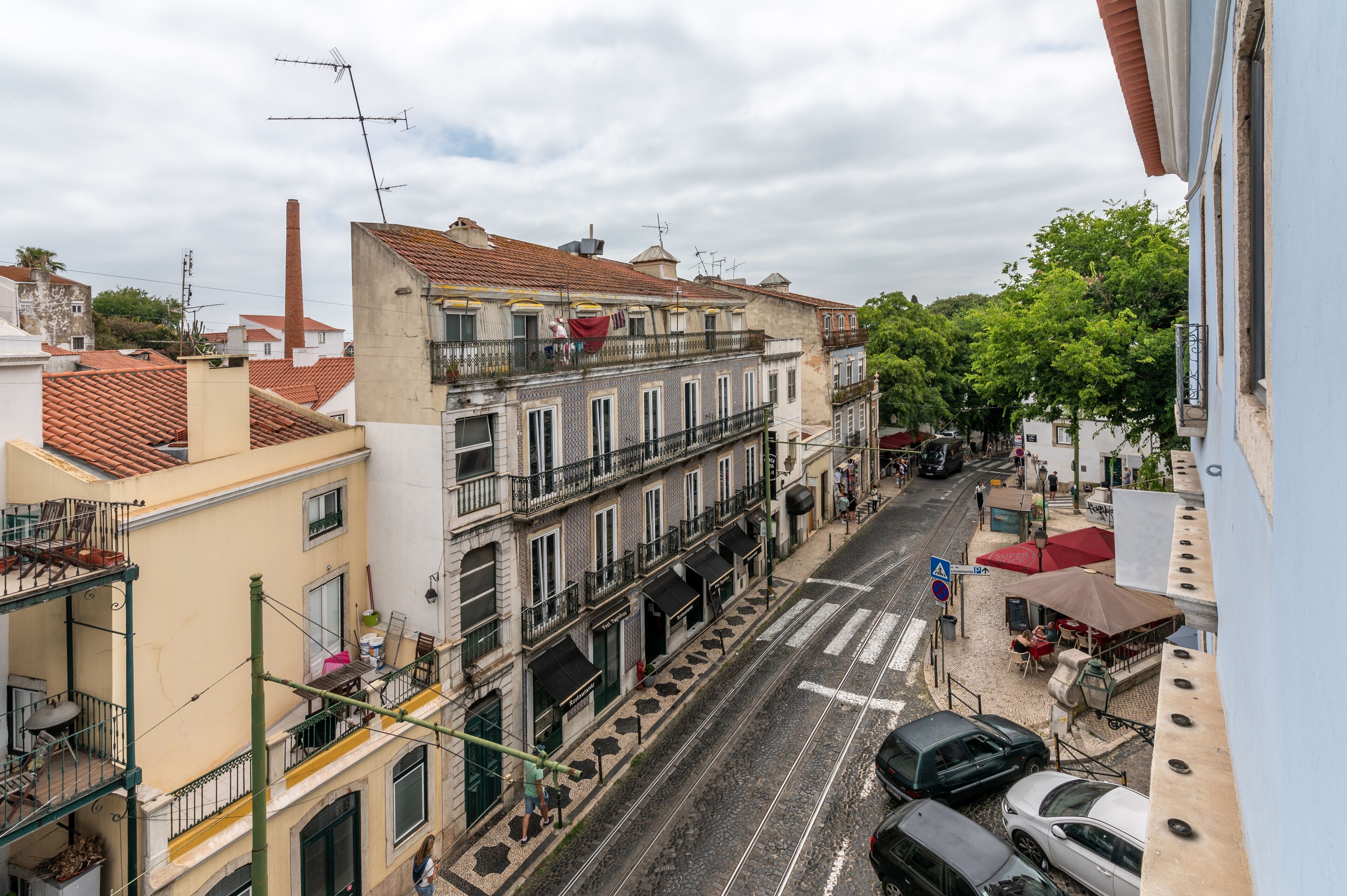Une vue de rue avec des immeubles, une ligne de tramway et des voitures garées.
