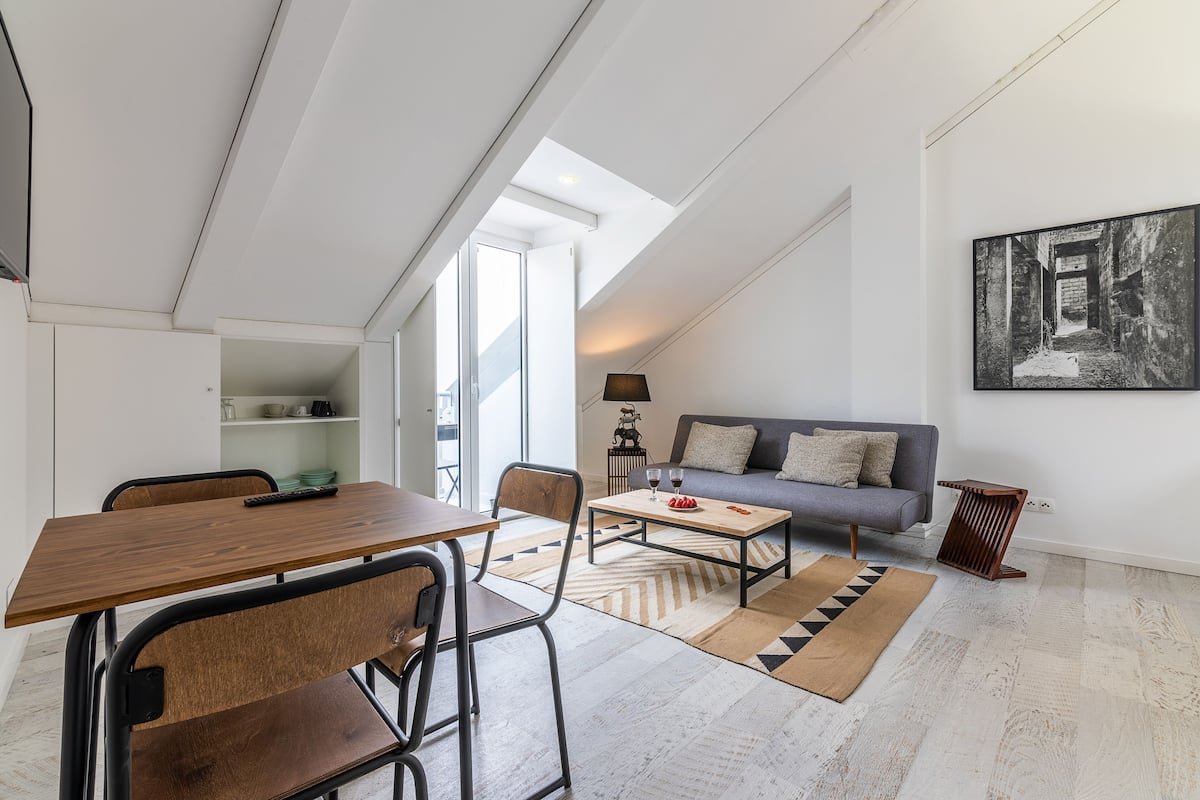 A modern living room with a dining area, a sofa, a coffee table, and a lamp.