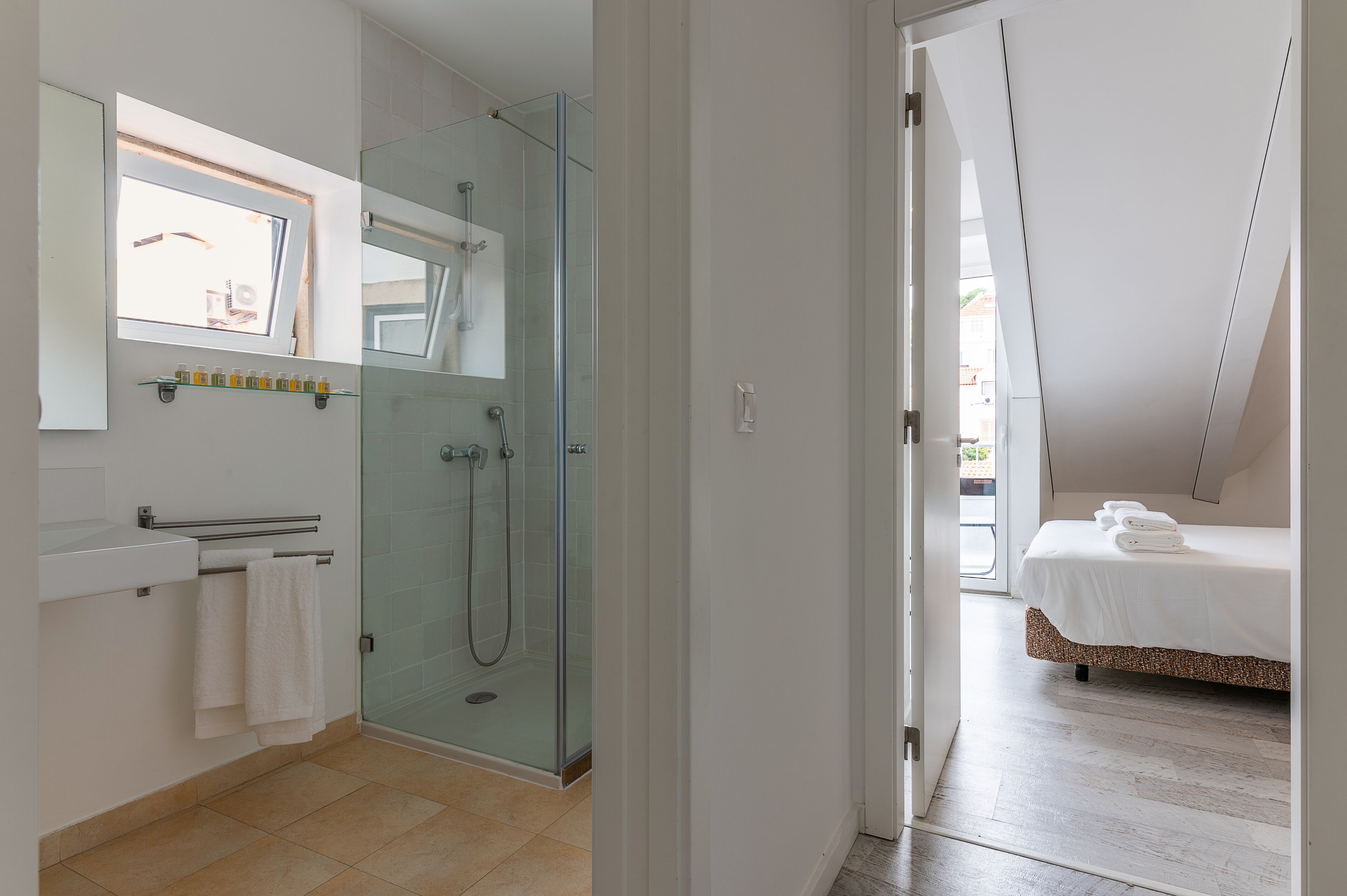 Un baño moderno con ducha de vidrio, lavamanos blanco y un perchero para toallas.