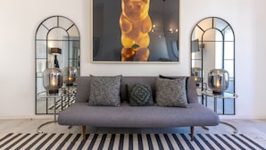 A modern living room with a grey sofa, two side tables with glass tops, and a large bear-shaped artwork above the sofa. - Portas do Céu Apartments (Lisbon)