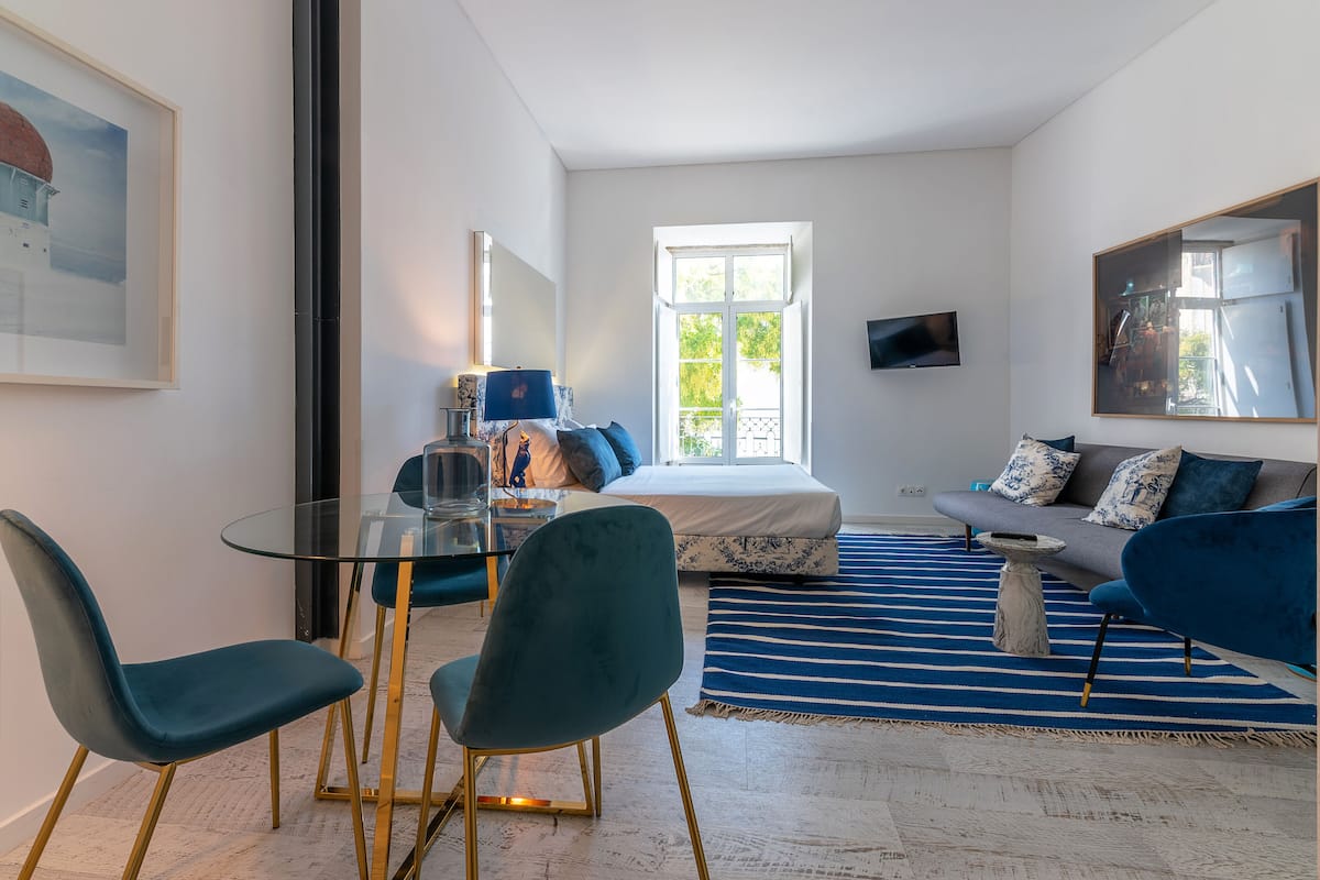 A modern bedroom with a bed, a sofa, a glass table, and chairs.