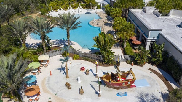 Ein Resort mit einem großen, zentral gelegenen Pool, umgeben von Palmen und Liegebereichen.