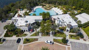 Luftaufnahme eines Resorts mit Schwimmbad, Palmen und Parkplatz.