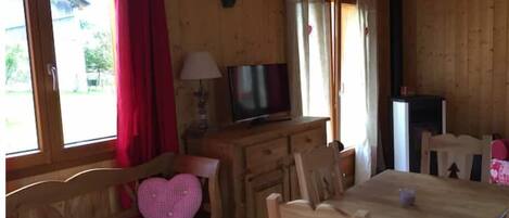 L’intérieur d’une cabane en bois, avec un banc en bois, une table et un téléviseur posé sur une commode.