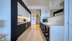 Una cocina moderna con una encimera larga, armarios negros y un refrigerador blanco.