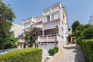 En flervåningsbostadsbyggnad med balkonger, en uppfart och en välskött trädgård.