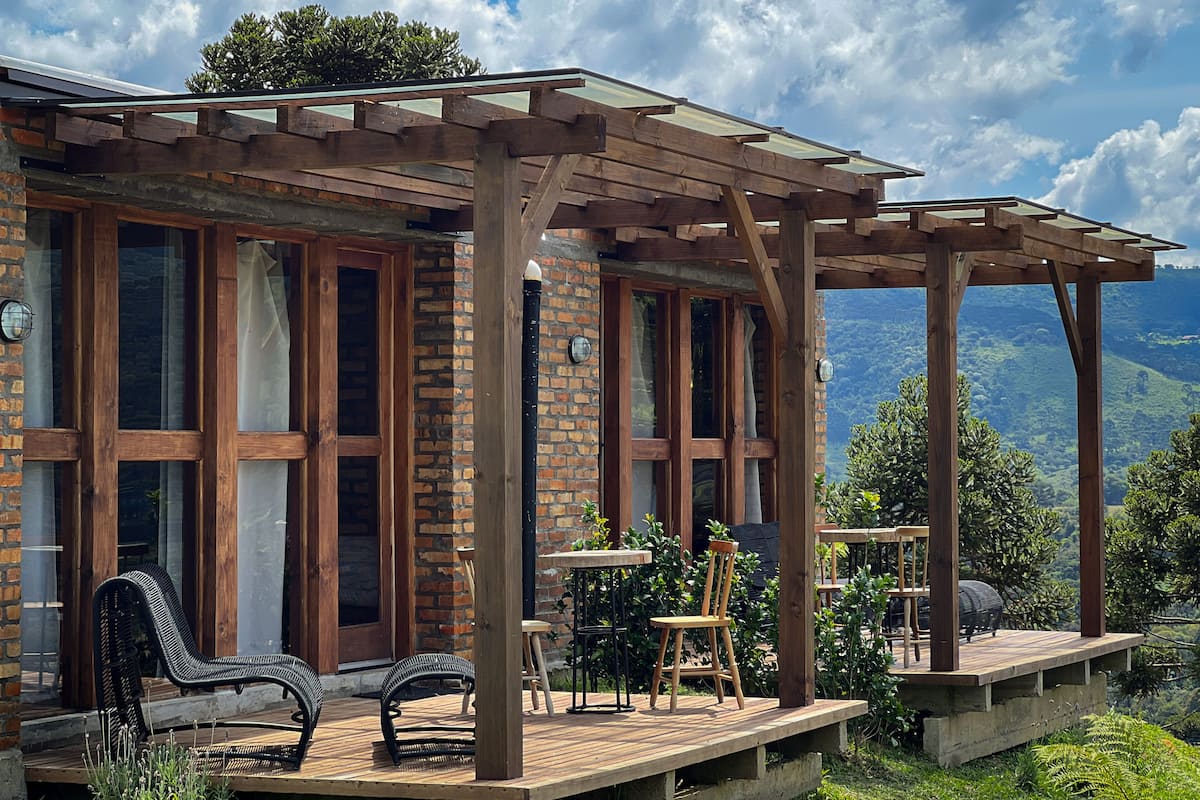 Eine Holzterrasse mit Gartenmöbeln, einer Pergola und Blick auf eine Berglandschaft.