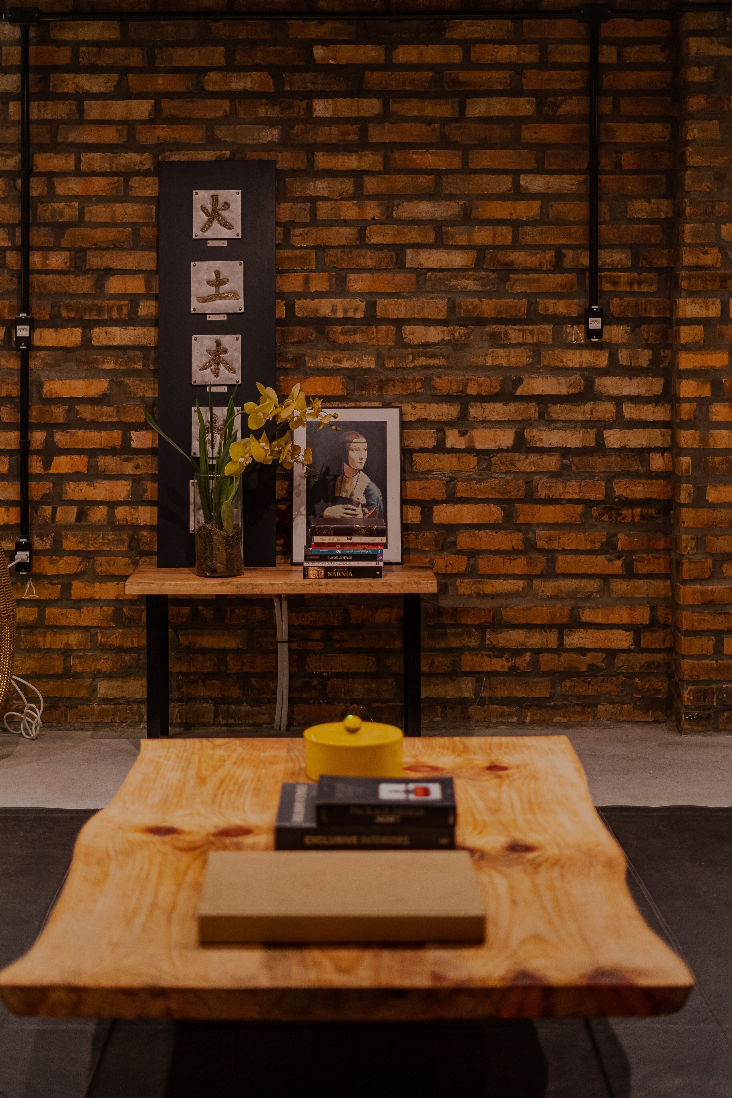 A wooden table with a framed picture, a vase with flowers, and a yellow candle.