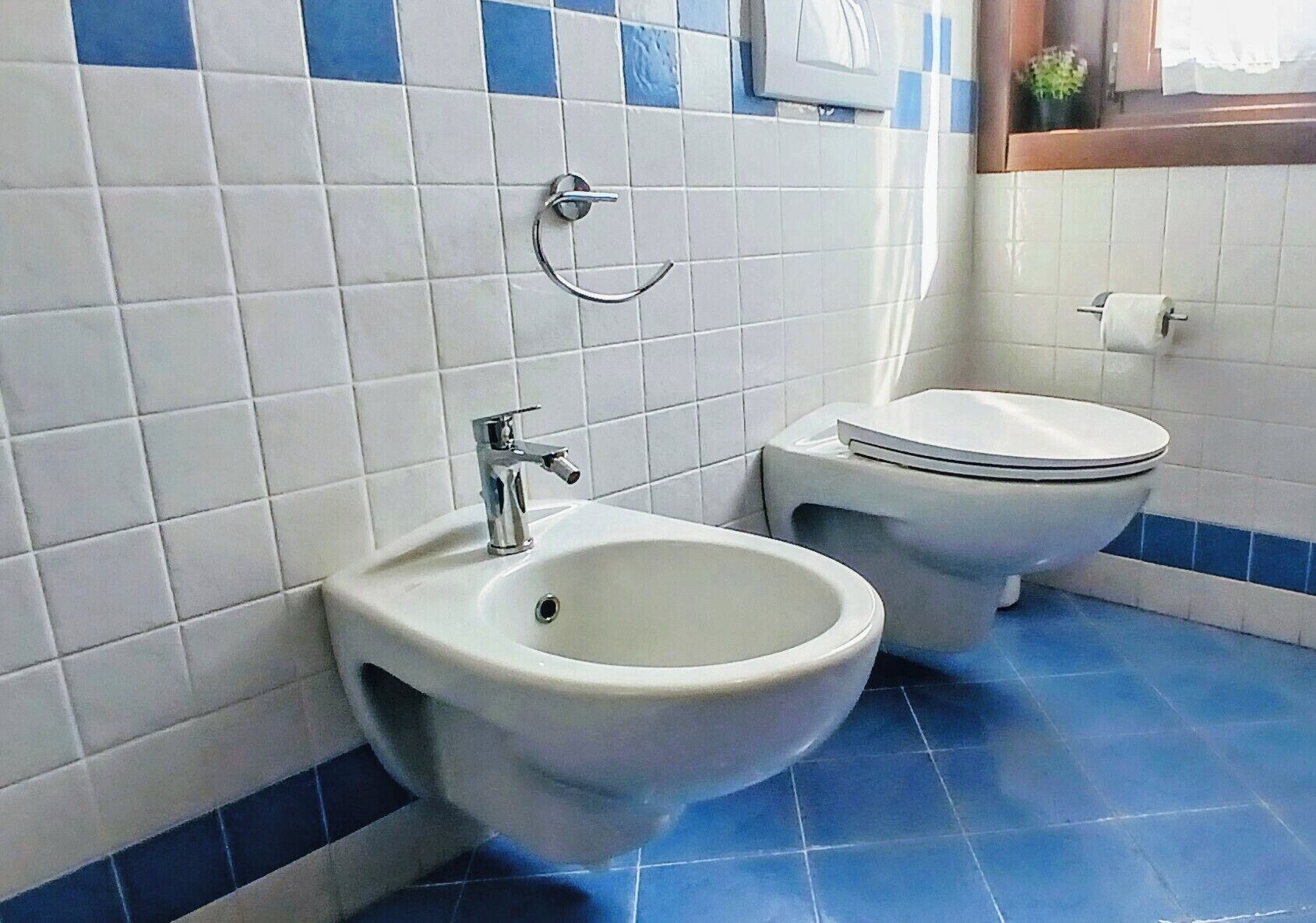 A bathroom with a bidet, a toilet, and a sink.