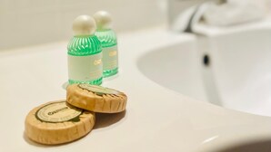 Un lavabo de salle de bain avec deux bouteilles vertes et deux savons en bois.