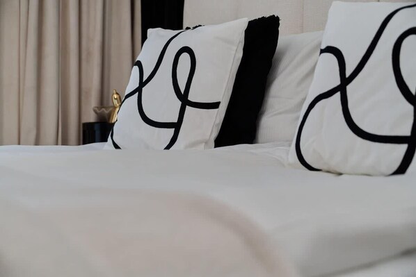 A bed with white bedding and black pillows with a simple design.