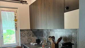 Een moderne keuken met een vaatwasser, fornuis en een raam met uitzicht op groen.