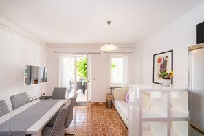 A modern kitchen with a white countertop, a hanging light fixture, and a dining area with patterned chairs and a table.
