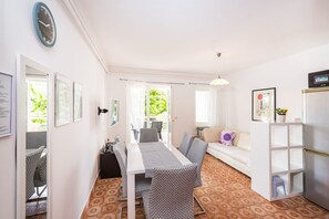 Un espace repas comprenant une table et des chaises, un canapé, un téléviseur et un réfrigérateur.