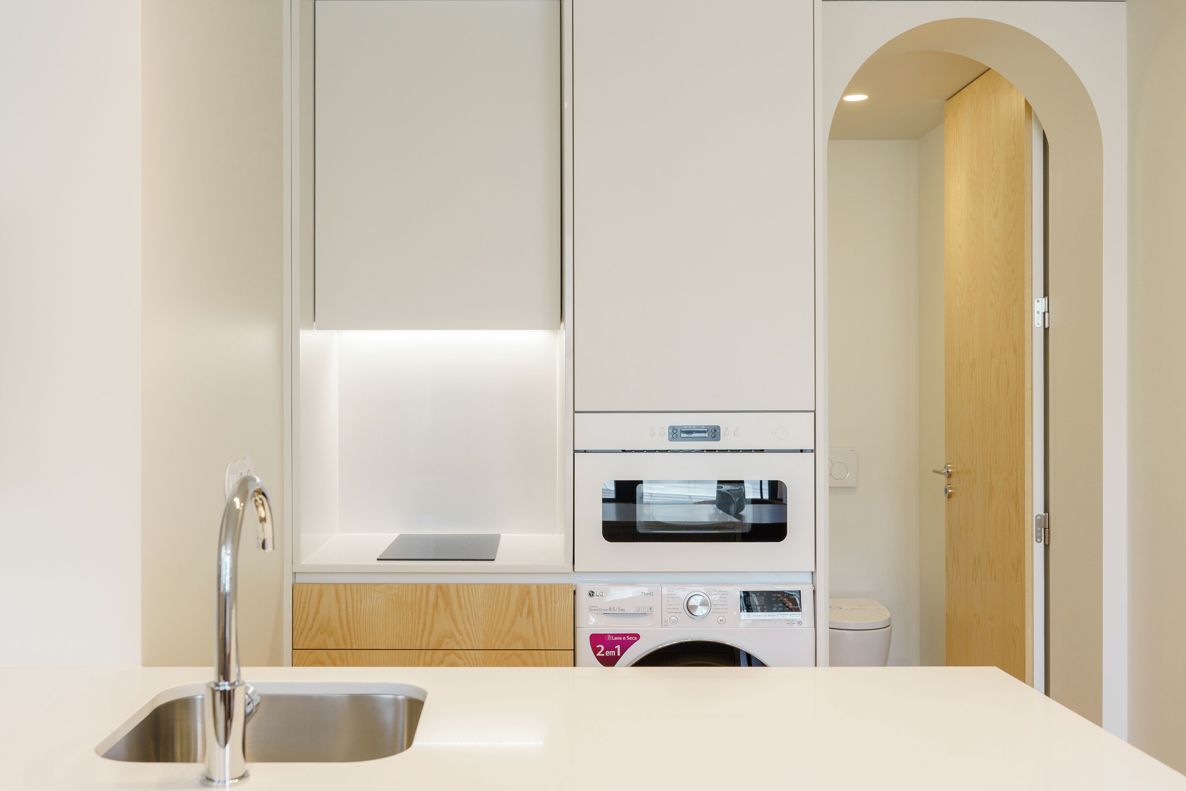Una cocina moderna con un lavamanos de acero inoxidable, horno empotrado y lavadora.