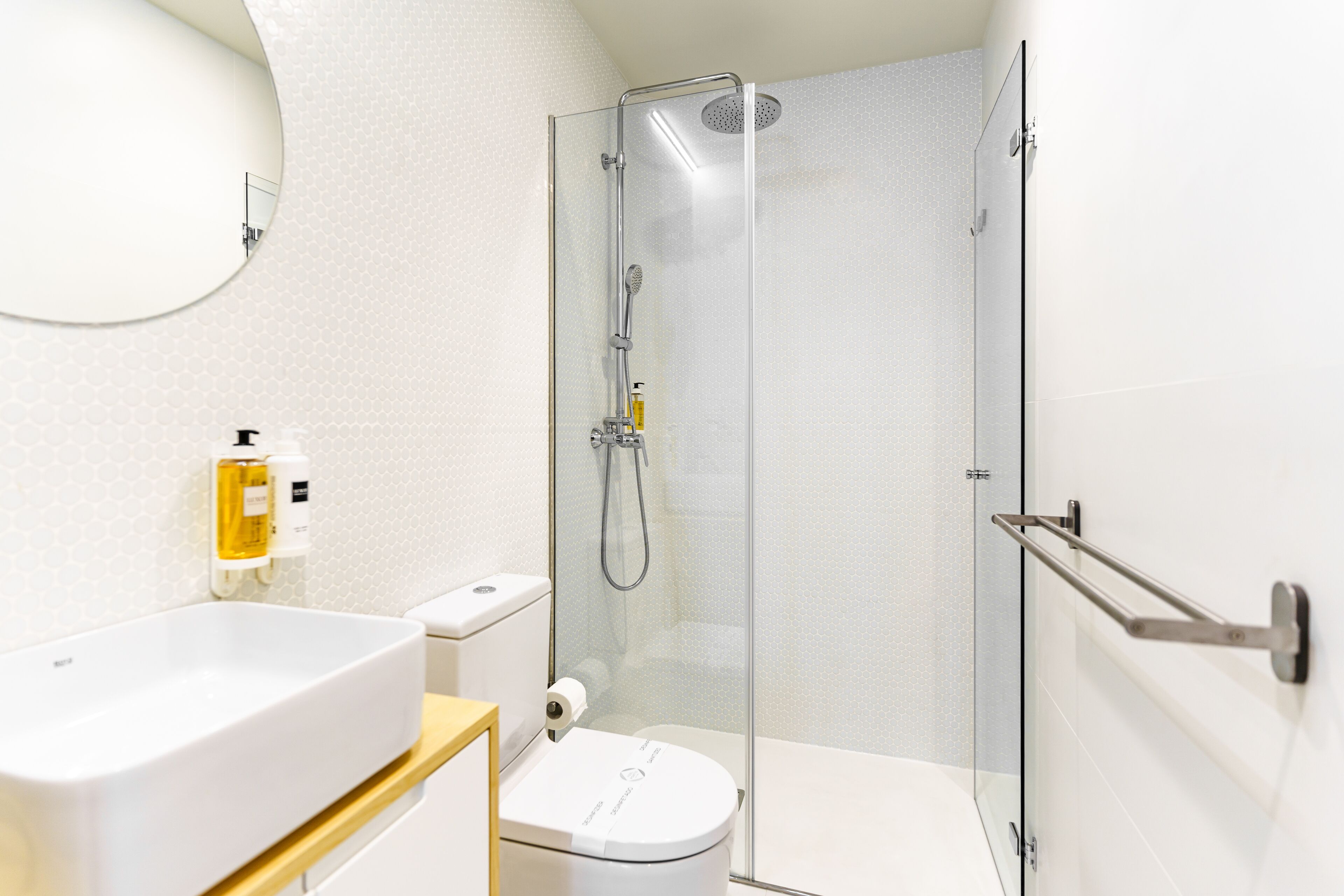 Un baño moderno con cabina de ducha de vidrio, un lavabo blanco y un inodoro.