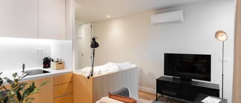 Una sala moderna con un sofá, televisor y un pequeño comedor.