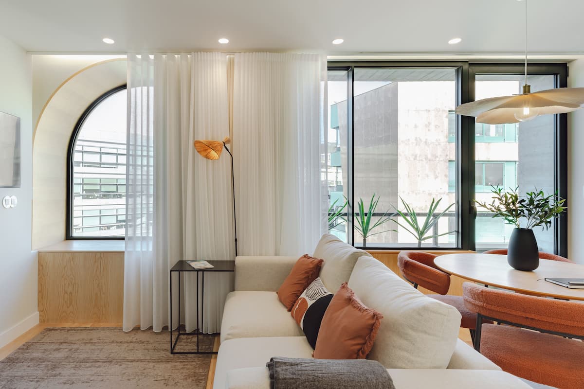 Una sala de estar moderna con un sofá, una mesa de comedor y un ventanal con cortinas.