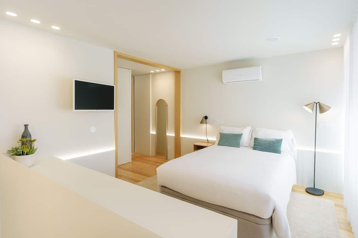 Un dormitorio moderno con una cama grande, mesitas de noche, un televisor y un aire acondicionado.