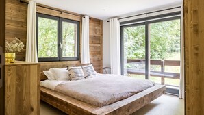 Un lit en bois donnant sur un paysage verdoyant.