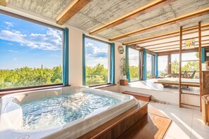 Quarto com hidromassagem, janelas amplas e vista para o verde.