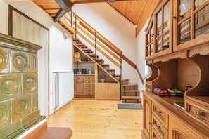 A wooden staircase leading to a second floor, a kitchen area with wooden cabinets, and a radiator. - Podhamer Wellness Vineyard Cottages (Ljutomer)