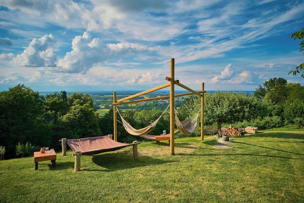 A hammock setup on a grassy hill with a view of the landscape. - Podhamer Wellness Vineyard Cottages (Ljutomer)