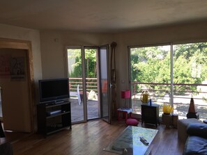 Relax in this inviting living room with a sofa, TV, and sliding glass door leading to an outdoor space.
