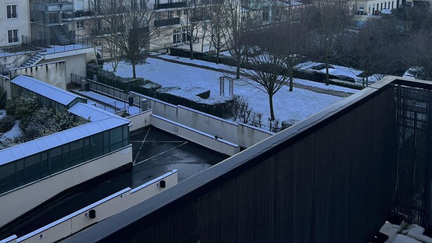 Zona residencial con suelo cubierto de nieve y edificios con balcones.