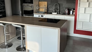 Una cocina moderna con una isla central, electrodomésticos de acero inoxidable y una pared de acento roja.