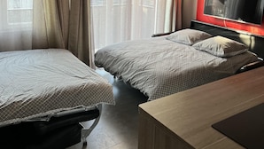 Habitación de hotel con dos camas, televisión y escritorio.