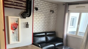 Una cocina moderna con encimera negra, sofá de cuero negro, una mesita y pared de ladrillo con una bandera estadounidense colgada.