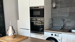 Una cocina moderna con horno empotrado, lavavajillas y encimera de madera.