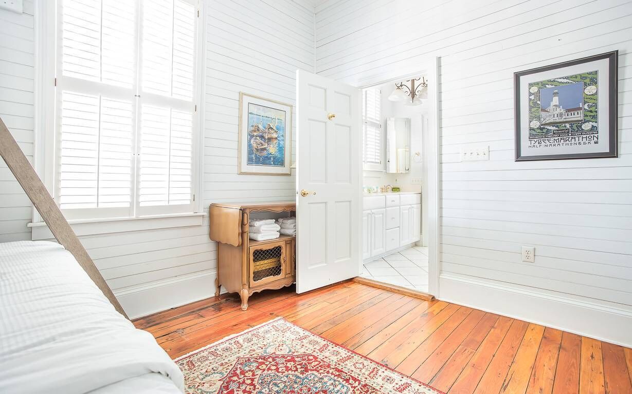 A bedroom with a bed, a wooden cabinet, a door, and a framed picture on the wall.