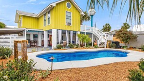 Ein gelbes Haus mit zwei Stockwerken und einem Pool im Hinterhof.