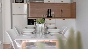 A modern kitchen with white cabinets, a stainless steel range hood, and a wooden countertop.