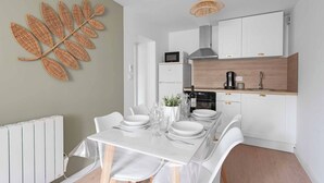 A modern kitchen with white cabinetry, a dining table set with white plates and glasses, and a decorative wall art piece.