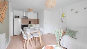 A compact, modern apartment with a kitchenette, a dining area, and a bedroom.