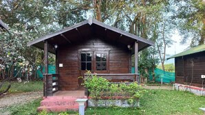 A wooden cabin with a porch, steps, and a small garden area. - Cocorico Stay Ya (Alibag)