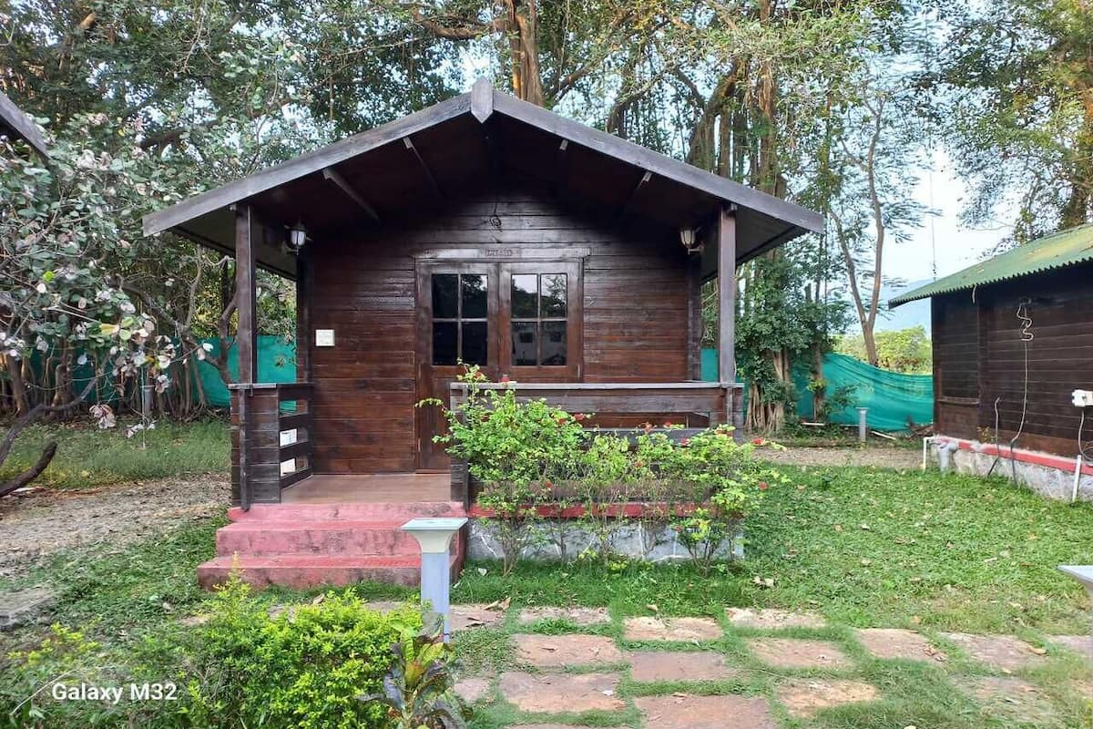 A wooden cabin with a porch, steps, and a small garden area.
