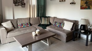 A modern living room with a sectional sofa, a coffee table, and decorative items. - Angelos elegant summer house  (Kassandra)