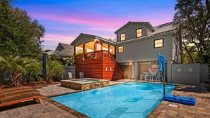 Un jardin avec une piscine, une terrasse en bois et une petite maison de jeu rouge.