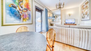 Een moderne woonkamer met een groot abstract schilderij, een kroonluchter, een televisie en een bank.