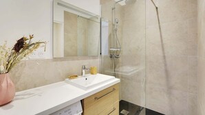 Une salle de bain moderne avec une douche à parois de verre, un lavabo blanc et un miroir au-dessus.